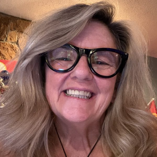 Portrait of Tish, owner of ItsTish LLC, smiling in black glasses